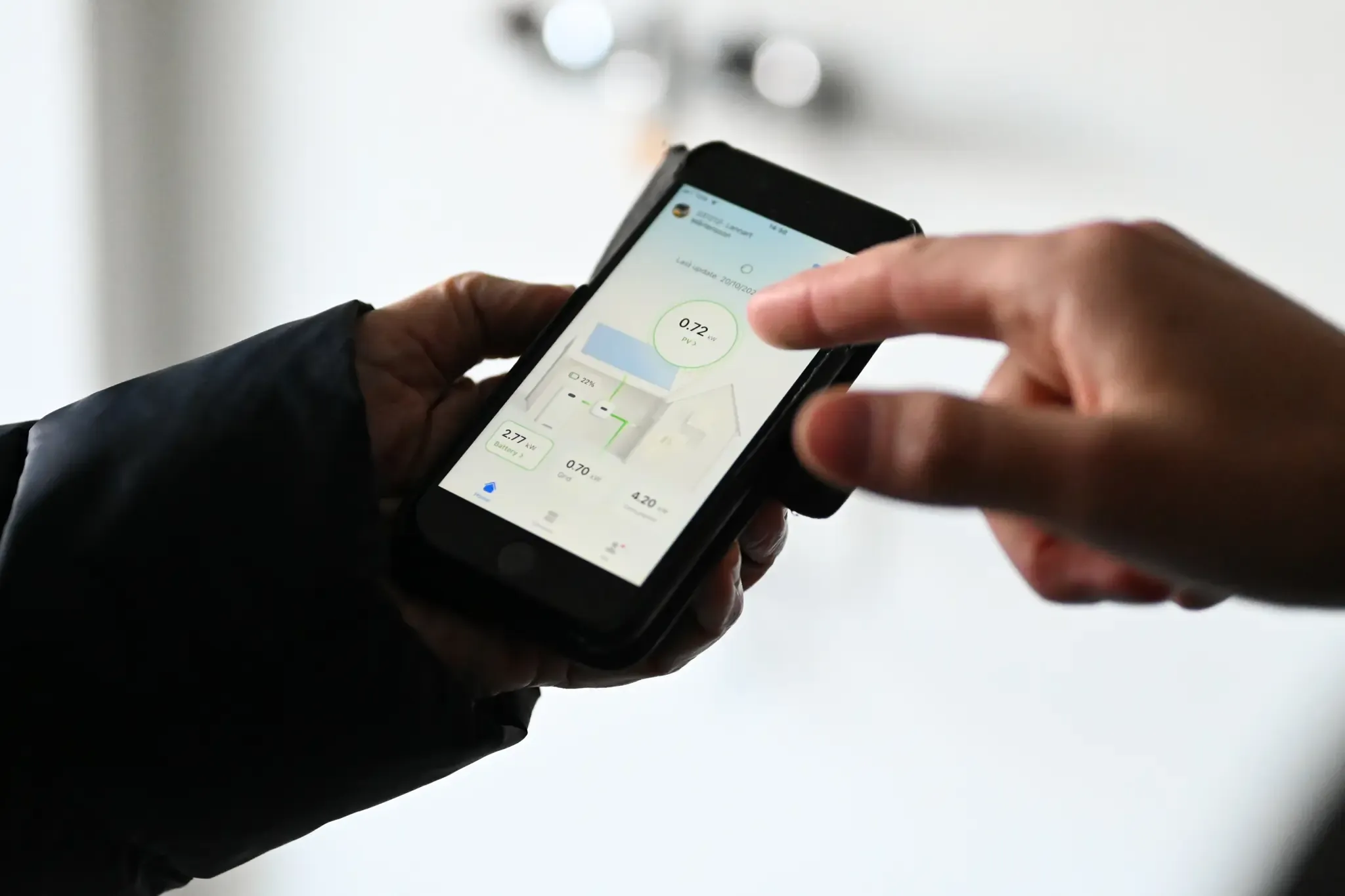 Person håller i telefon med Sesols app som kan styra och följa upp solcellsproduktion