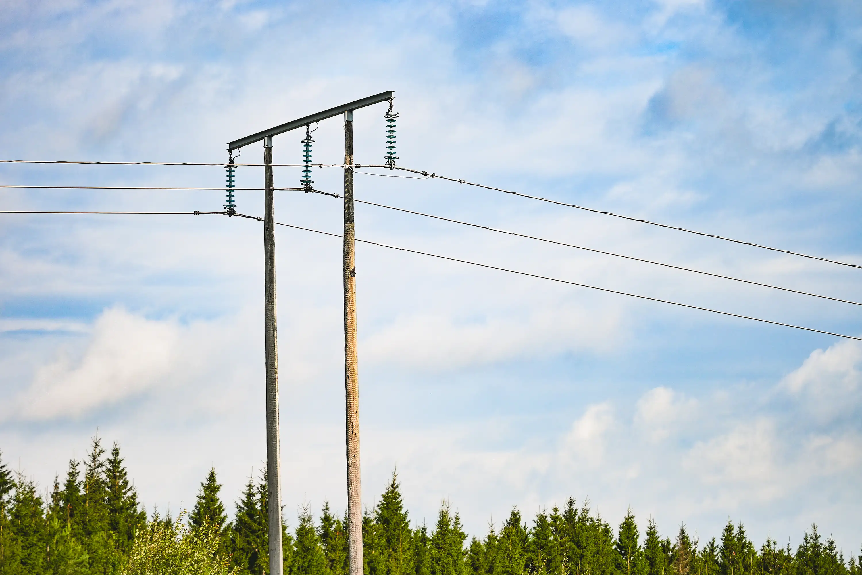 Kraftledning i naturen mot blå himmel og skog