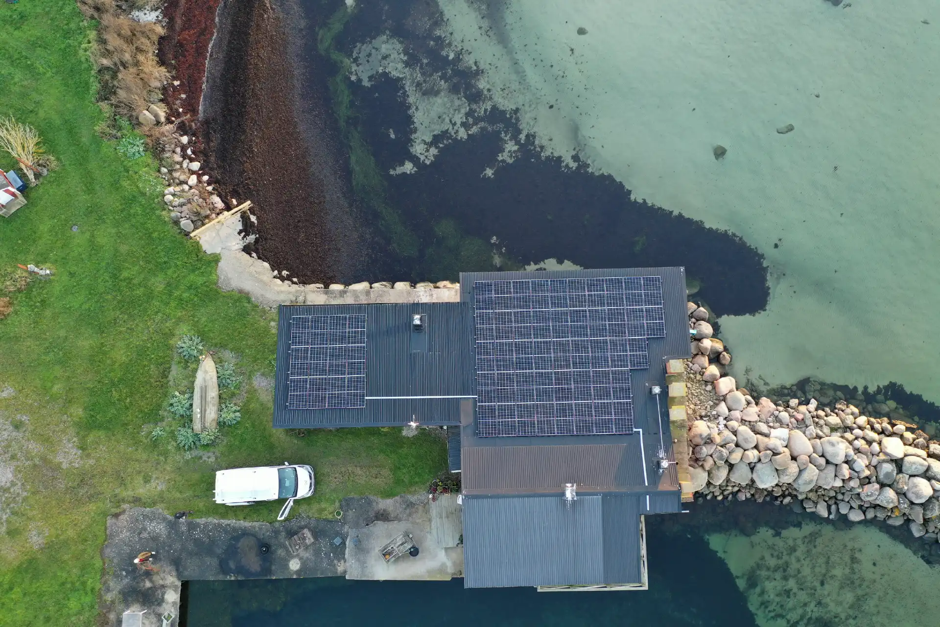 Solcellsanläggning ovanifrån villatak vid havet