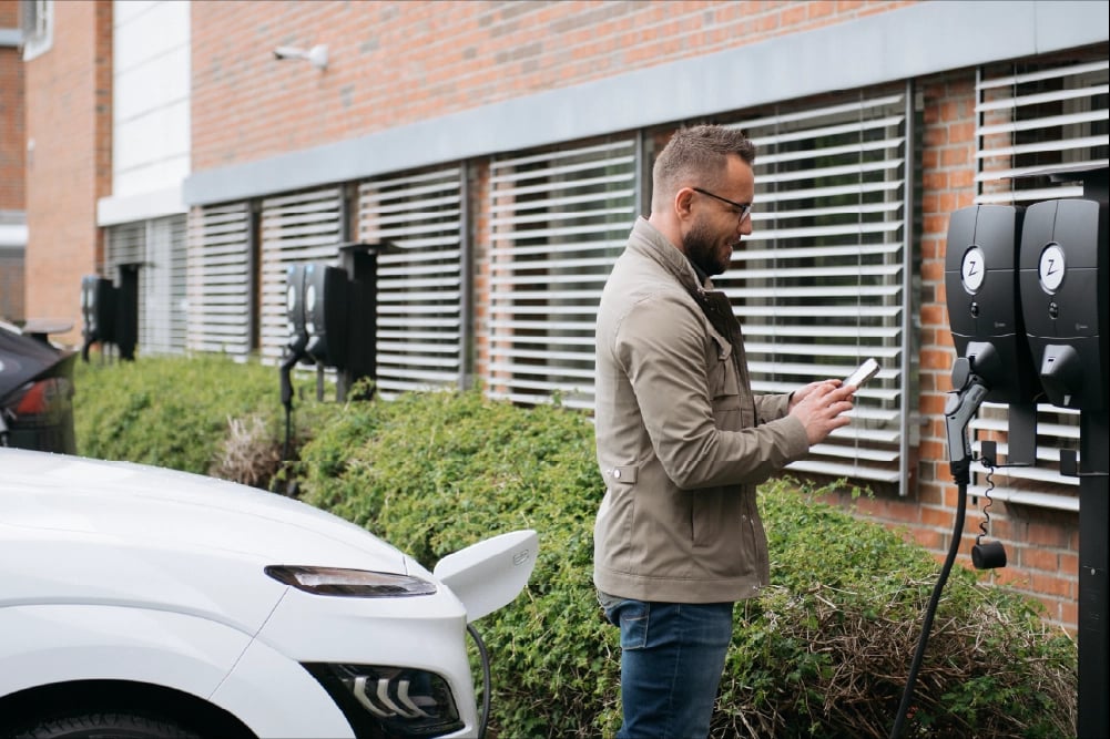 En man startar elbilsladdning på företagets parkering